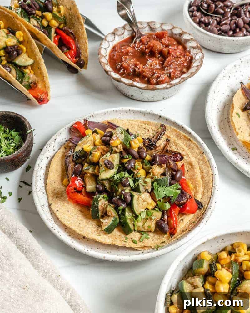 Roasted Harvest Tacos 14 Plated Vegan Roasted Veggie Tacos on a white plate with fresh ingredients in the background, set on a bright white surface.