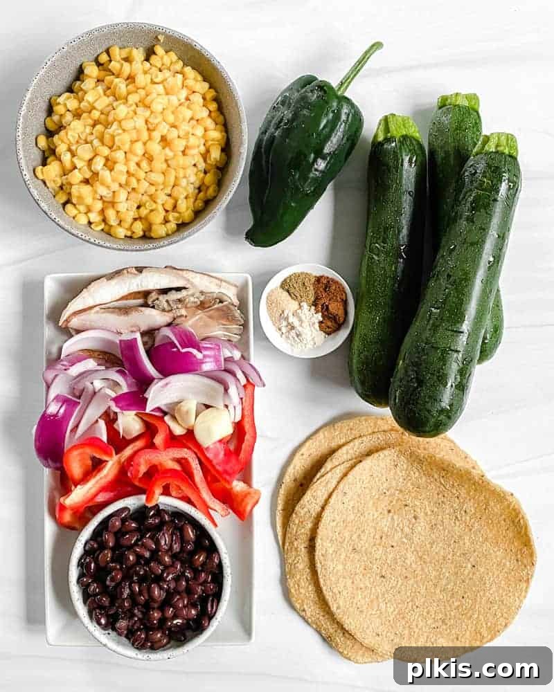 Roasted Harvest Tacos 3 A vibrant collection of vegan roasted veggie taco ingredients laid out on a white background, including fresh corn, zucchini, peppers, and various spices.