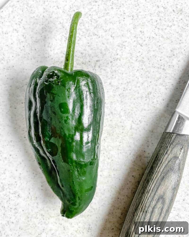 Roasted Harvest Tacos 5 green pepper with knife against a white background, ready to be diced.
