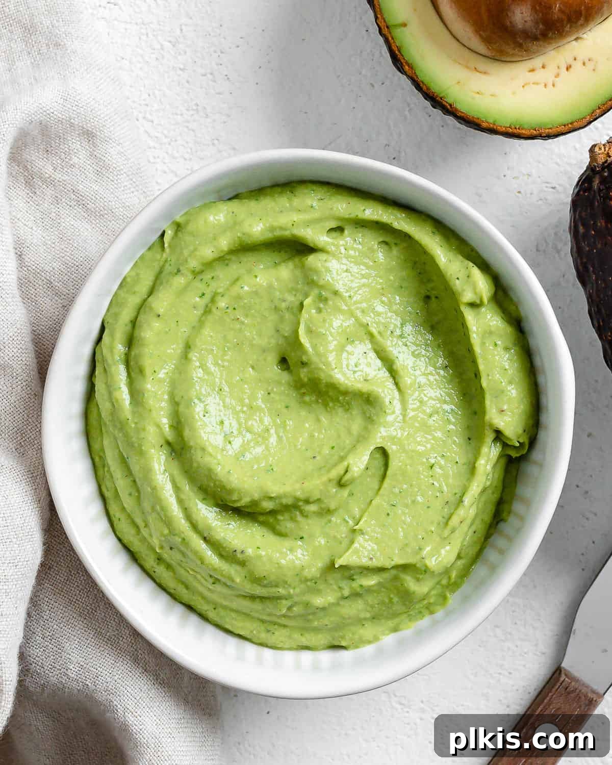 Effortless Avocado Cream 2 Completed Avocado Cream in a white bowl with an avocado in the background.