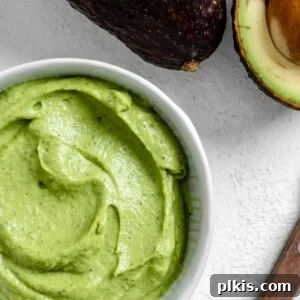 completed Avocado Cream in a white bowl with an avocado in the background
