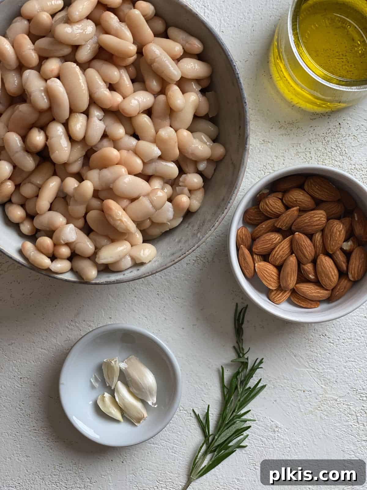 Plant-Powered Bean Dip 3 ingredients measured out for Vegan Bean Dip against a white surface