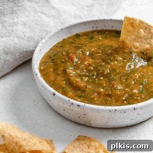 Zesty Tomatillo Green Chili Salsa 14 completed Stovetop Tomatillo Salsa in a bowl with a chip being dipped in it