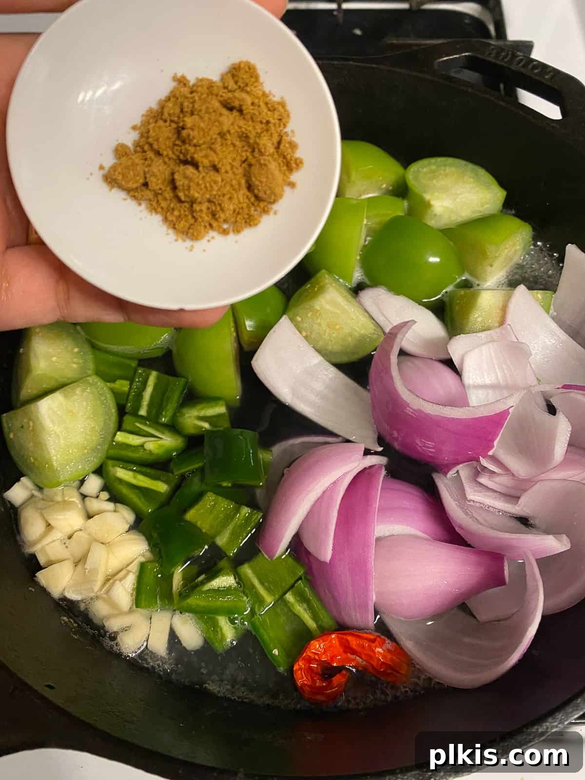 Zesty Tomatillo Green Chili Salsa 6 Adding dried cumin seasoning to the pan of chopped vegetables for tomatillo salsa.