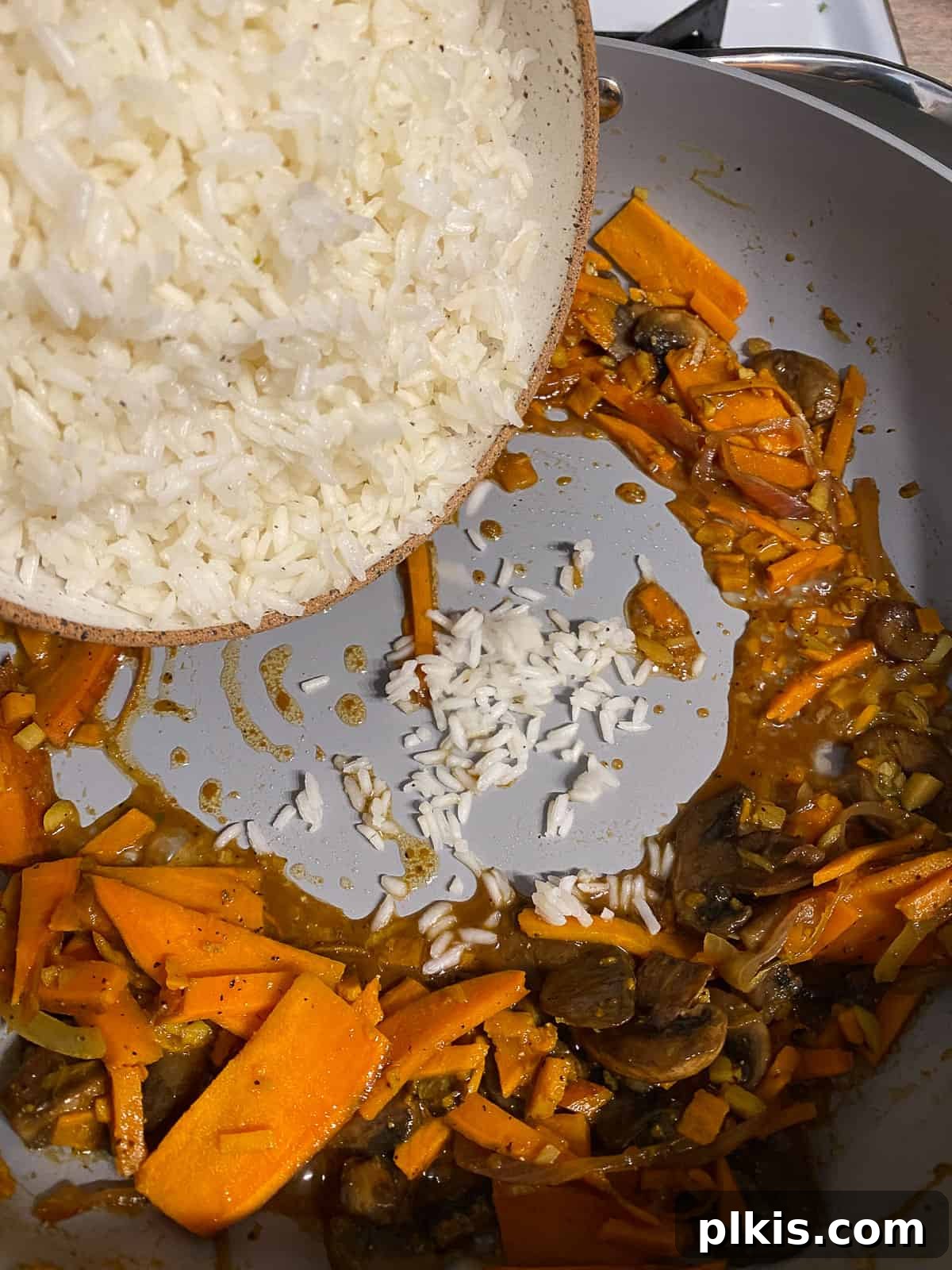 Nourishing Sweet Potato Fried Rice 13 Cooked rice being added to the skillet with a portion of the vegetables.