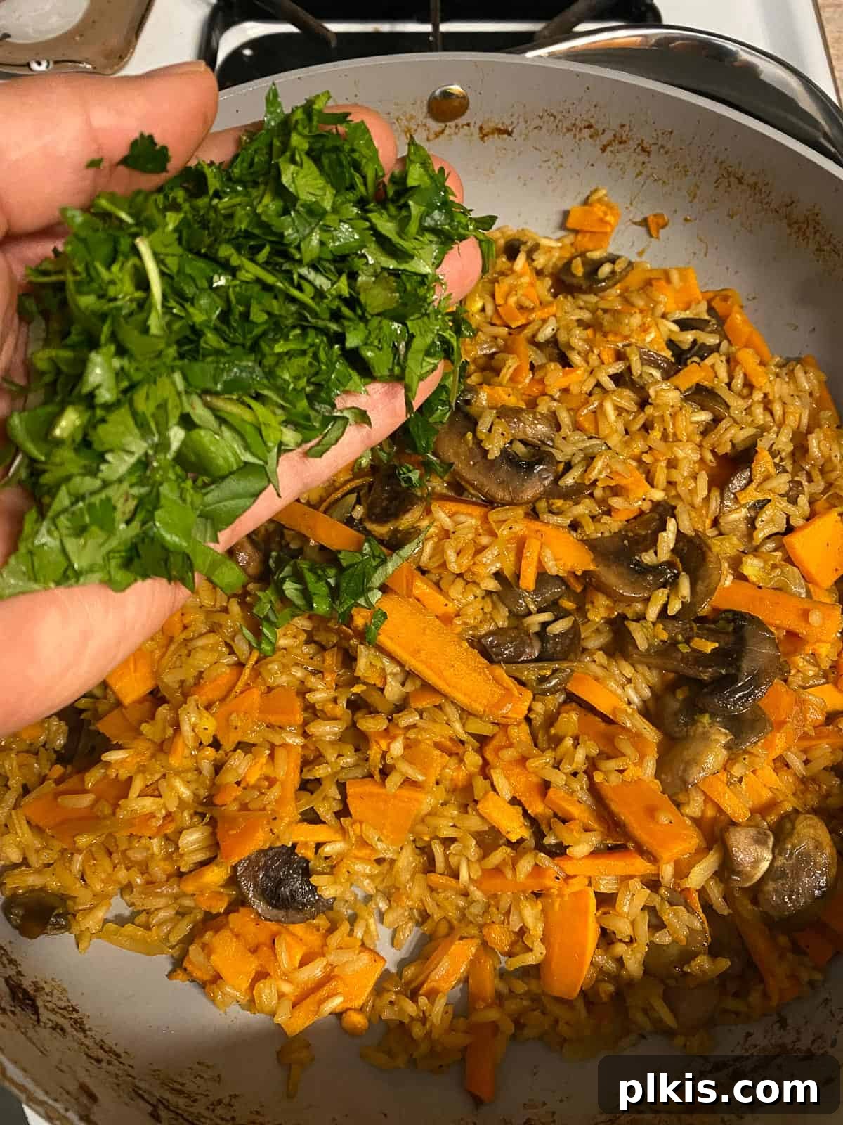 Nourishing Sweet Potato Fried Rice 16 Fresh green herbs, such as cilantro or basil, being stirred into the cooked fried rice.