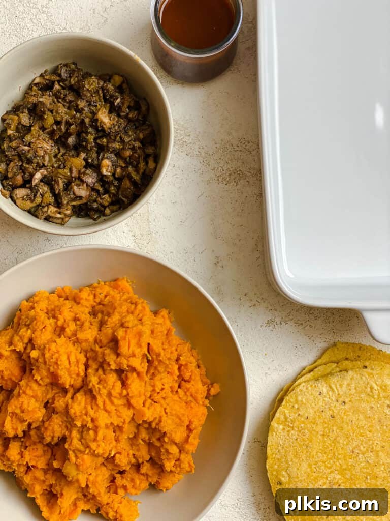 Golden Sweet Potato Rolls 11 A selection of ingredients for sweet potato enchiladas, including mashed sweet potato, cooked mushrooms, and tortillas, laid out on a white surface for assembly.