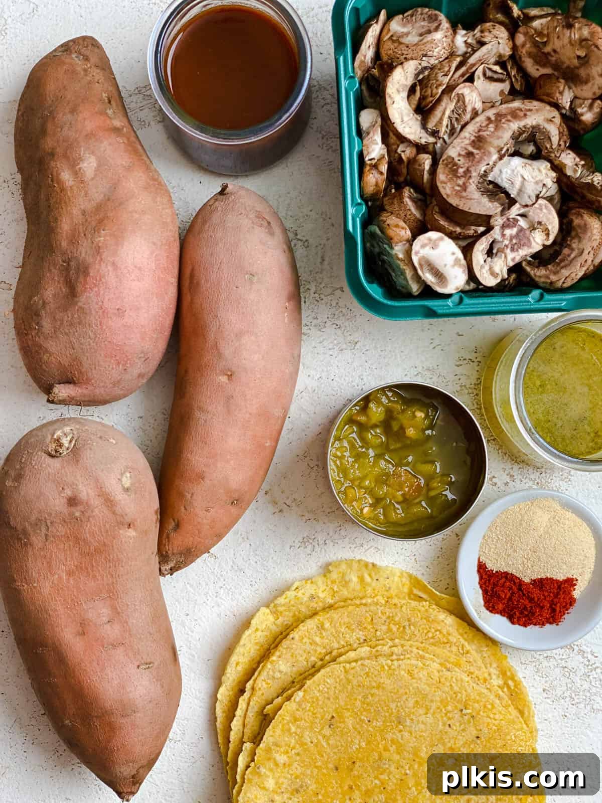 Golden Sweet Potato Rolls 3 Various fresh ingredients for vegan sweet potato enchiladas, including diced sweet potatoes, sliced mushrooms, and a can of green chilies, neatly arranged on a white surface.
