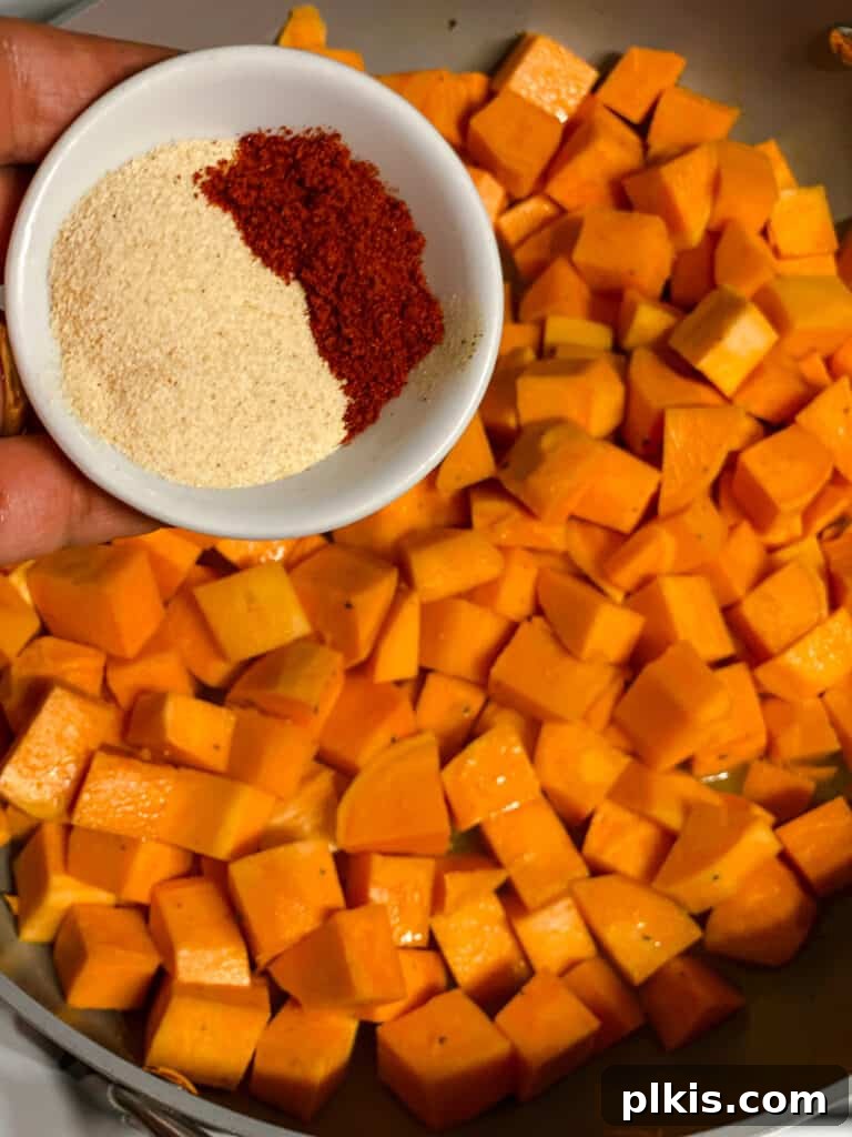 Golden Sweet Potato Rolls 5 Close-up process shot of spices being sprinkled over cooking sweet potatoes in a pan, enhancing their flavor.