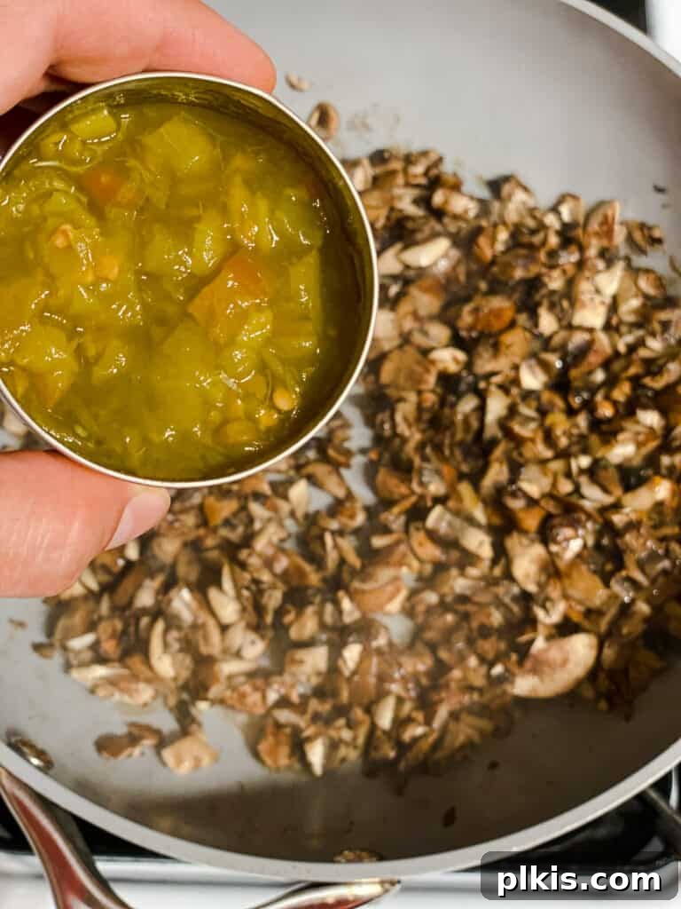 Golden Sweet Potato Rolls 7 Process shot showing diced green chilies being added to the cooked mushrooms in a skillet, ready to be combined.