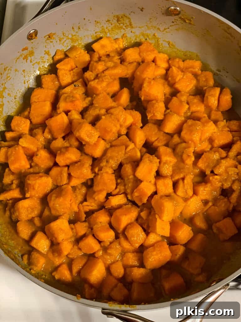 Golden Sweet Potato Rolls 8 Process shot of sweet potatoes cooking gently in a pan, becoming tender and infused with flavor.