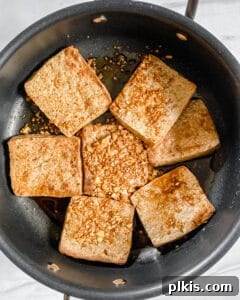 Sweet and Spicy Tofu Stir-Fry 7 Process shot of browning tofu fillets in a black pan, showing golden-crisp edges.