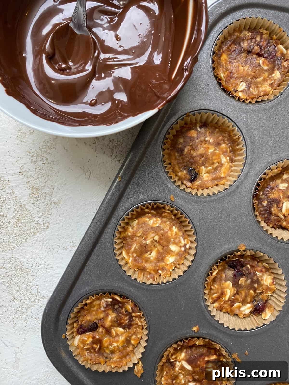 Chilled Peanut Butter Perfection 6 A process shot showing the peanut butter and oat mixture pressed firmly into the individual cavities of a mini-muffin tin, forming the base of the cups.