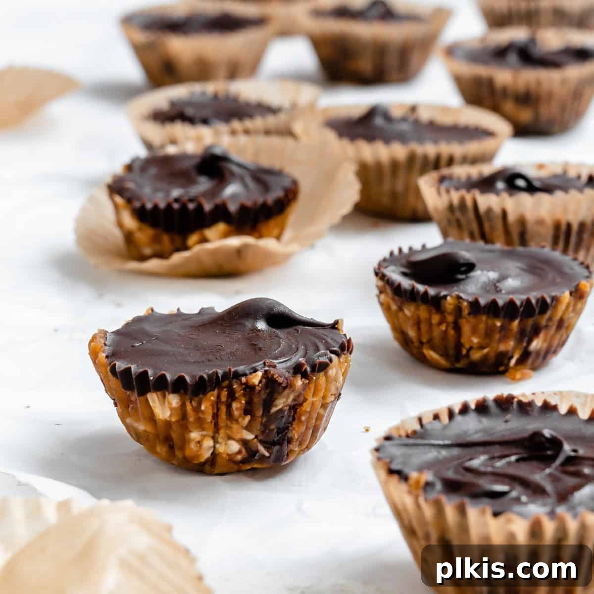 Chilled Peanut Butter Perfection 8 A vibrant, close-up shot of several completed No-Bake Peanut Butter Cups, perfectly set and showcasing their appealing chocolate topping and rich base, arranged artfully on a white surface.