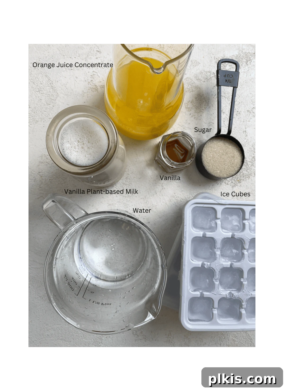 Creamy Orange Dream Smoothie 3 Ingredients for Easy Orange Julius Smoothie Recipe measured out against a white surface, including frozen orange juice concentrate, plant-based milk, granulated sugar, vanilla extract, and a bowl of ice cubes.