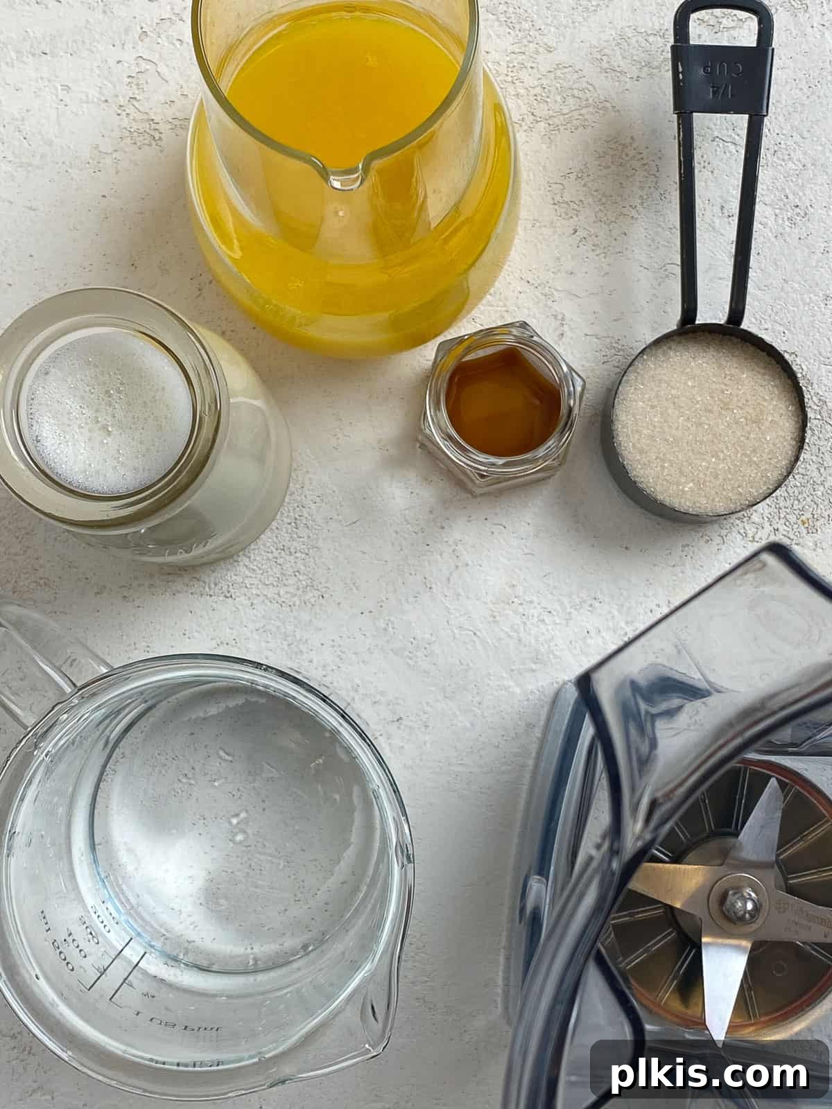 Creamy Orange Dream Smoothie 4 Image showing orange juice concentrate, sugar, vanilla, plant-based milk, and water measured out and ready to be added to a blender.