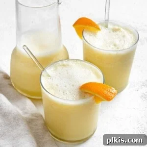 Creamy Orange Dream Smoothie 7 Two completed Easy Orange Julius Smoothies in glass cups with a pitcher in the background, showing the frothy, creamy texture.