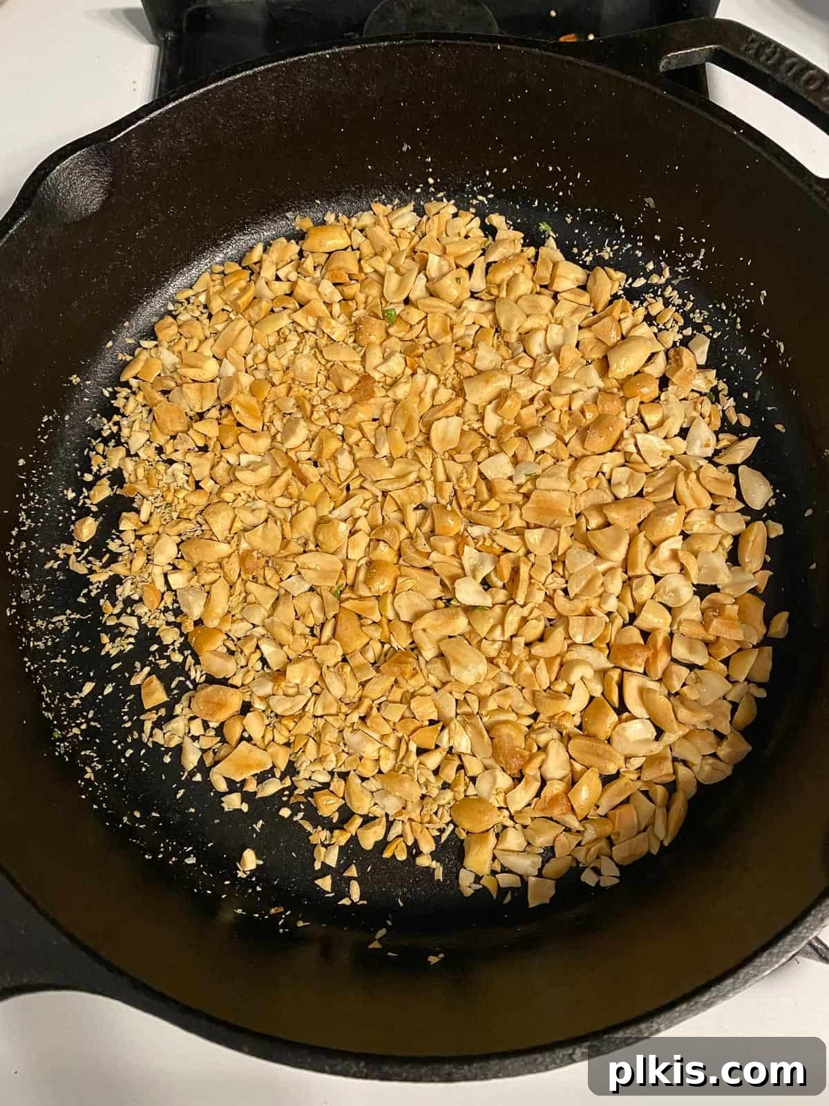 Process shot of peanuts toasting on a pan, turning golden.