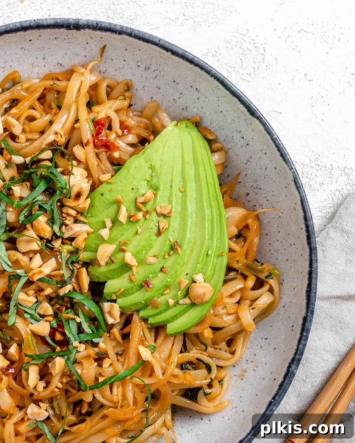 Completed Vegan Vegetable Pad Thai plated against a light background with fresh lime and herbs.