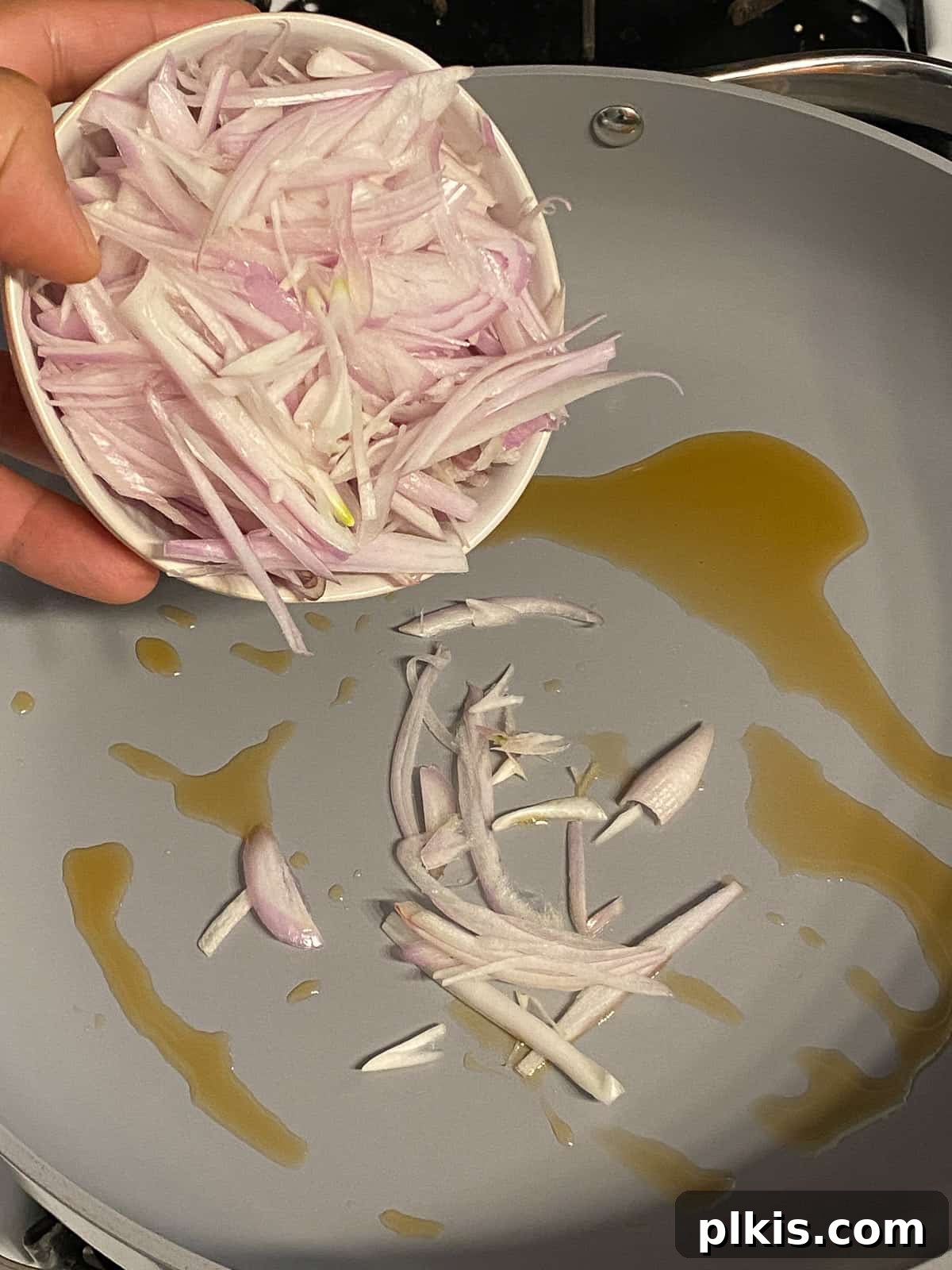 Process of adding sliced onions to a pan of hot oil.