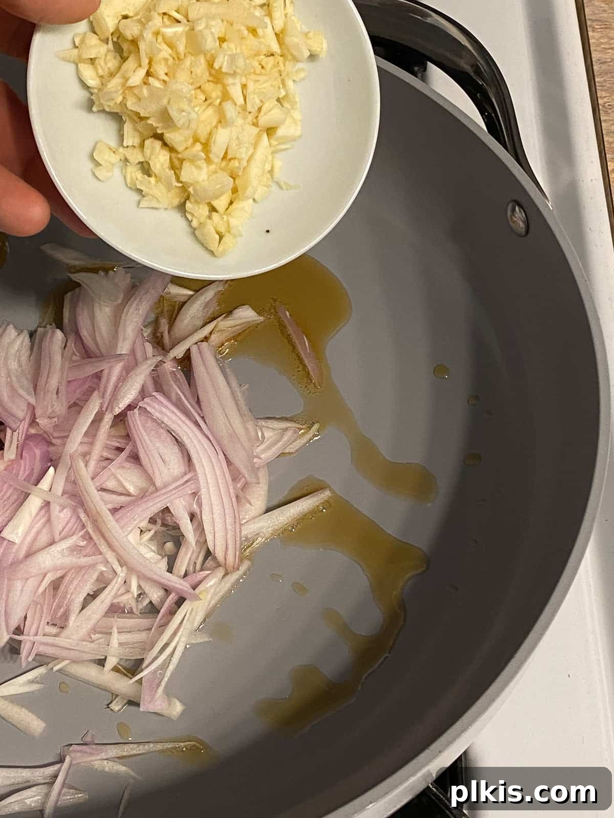 Process of adding minced garlic to a hot pan.