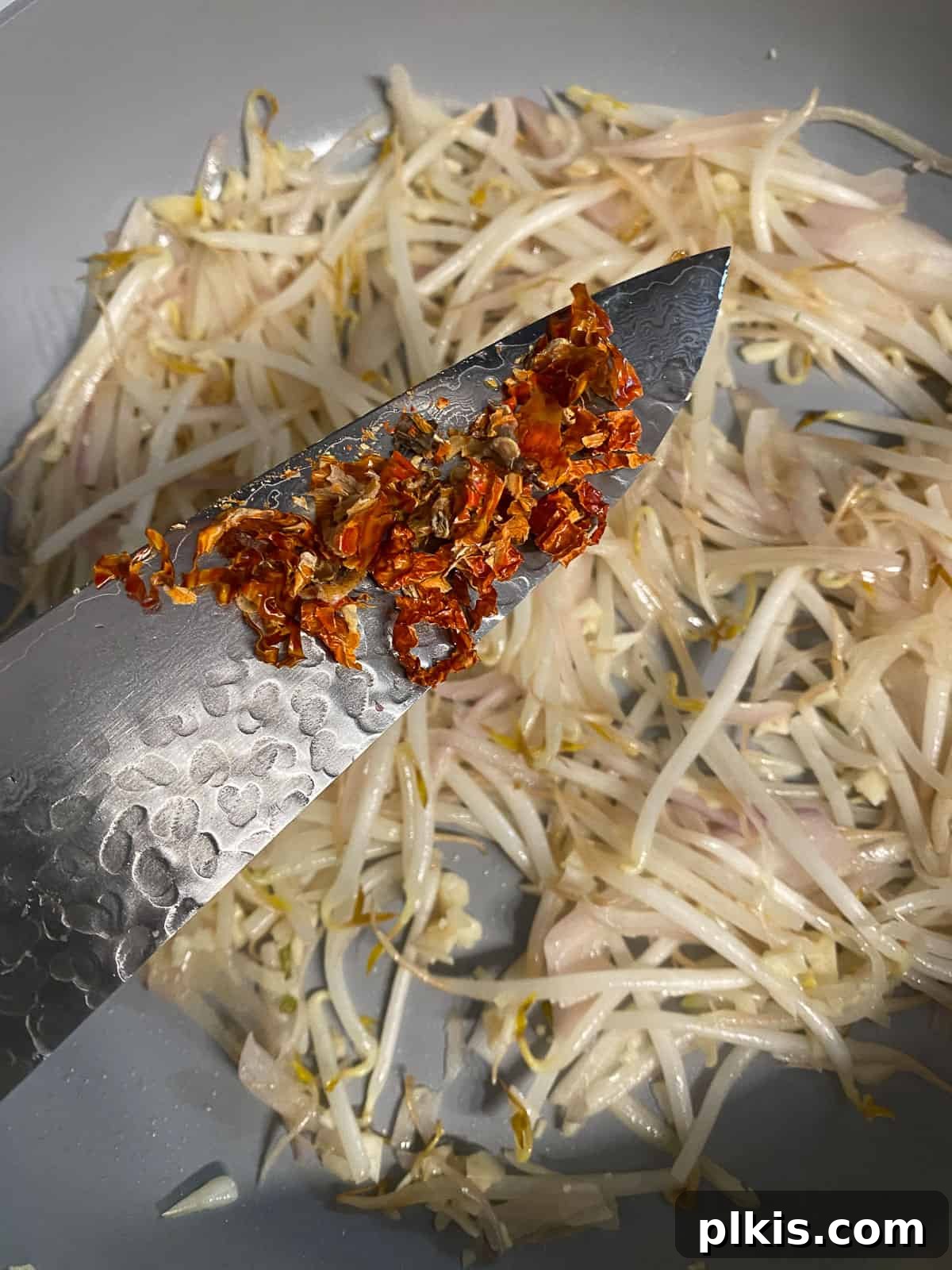 Process of adding finely chopped shallot to a hot pan.