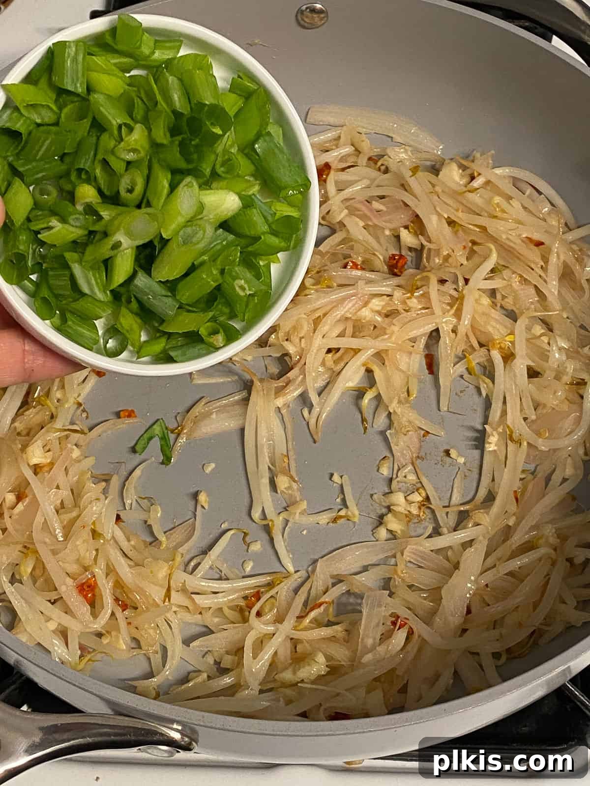 Process of adding chopped green onions to the pan with aromatics.