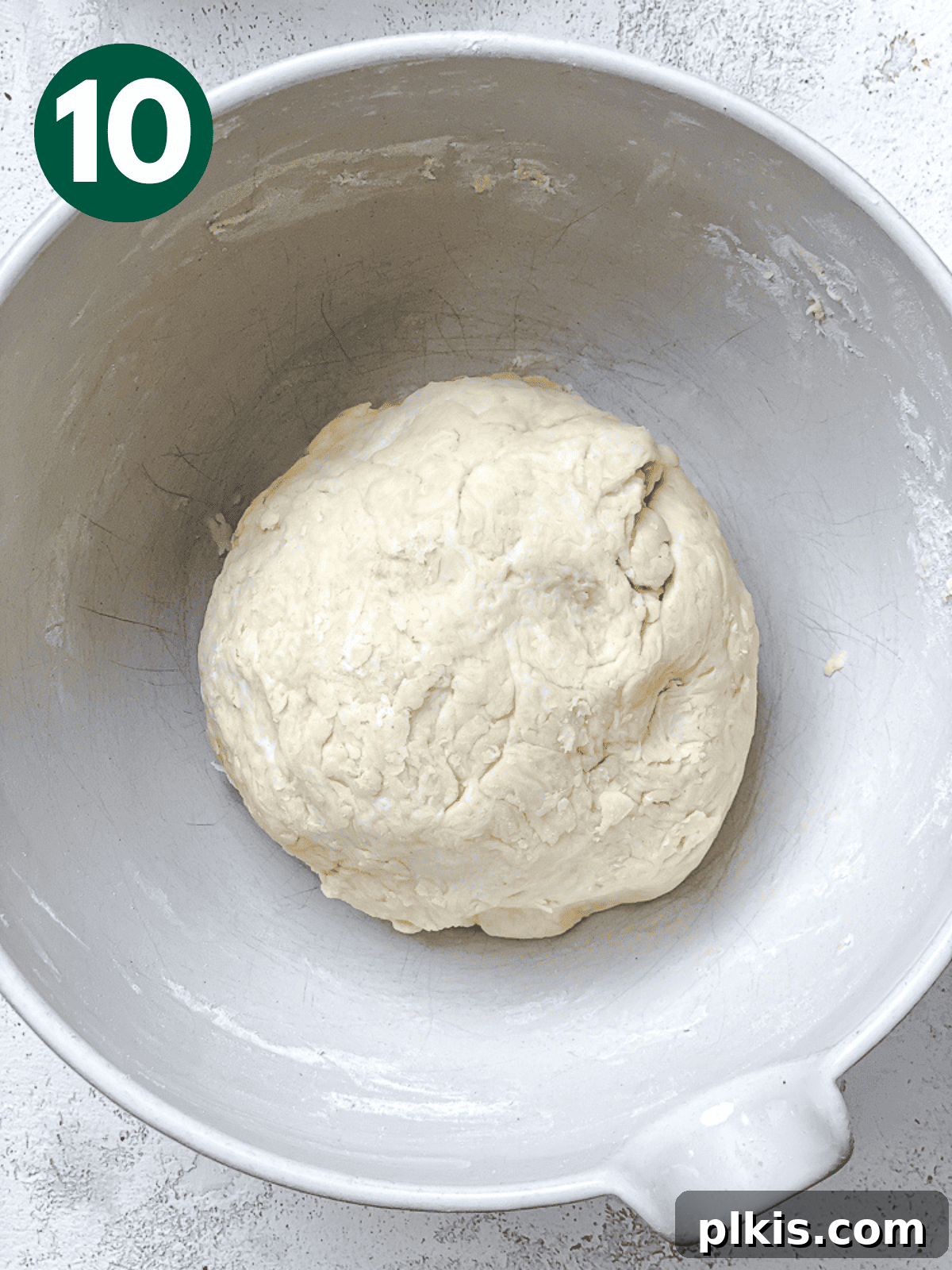 Heavenly Vegan Cinnamon Rolls 13 A smooth, round ball of kneaded dough resting in a white bowl.