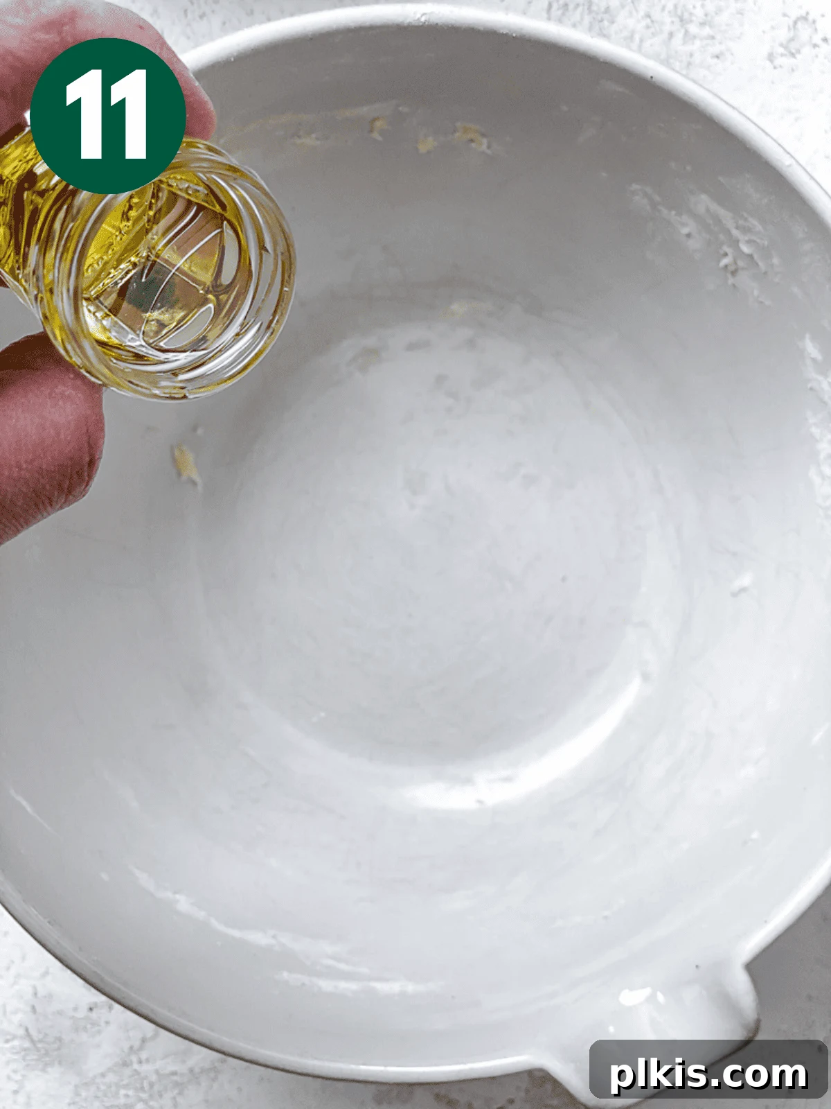 Heavenly Vegan Cinnamon Rolls 14 Pouring neutral oil into a large white bowl, preparing it for the dough's first rise.