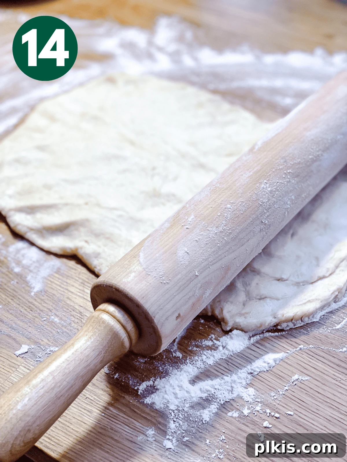 Heavenly Vegan Cinnamon Rolls 17 Using a wooden rolling pin to carefully roll out cinnamon roll dough into a rectangular shape on a floured surface.