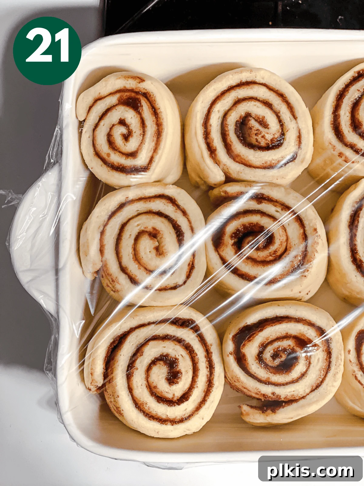 Heavenly Vegan Cinnamon Rolls 24 Unbaked cinnamon rolls nestled in a baking dish, covered with plastic wrap for their second rise.