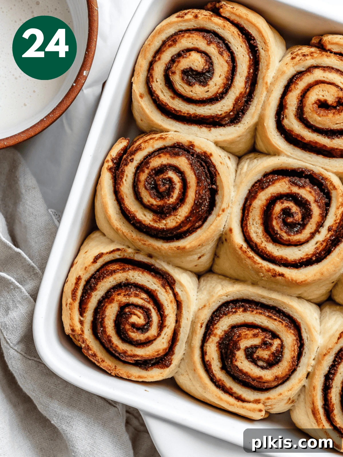 Heavenly Vegan Cinnamon Rolls 27 Freshly baked vegan cinnamon rolls in a white baking dish, golden brown and puffed up.