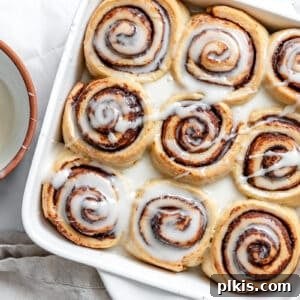 Heavenly Vegan Cinnamon Rolls 31 vegan cinnamon rolls in a white baking pan with vanilla icing on top.