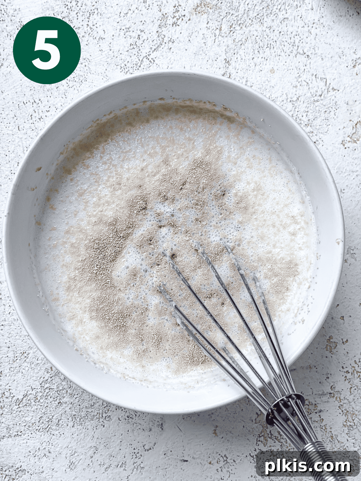 Heavenly Vegan Cinnamon Rolls 8 Whisking yeast into the vegan buttermilk mixture in a white bowl until combined.
