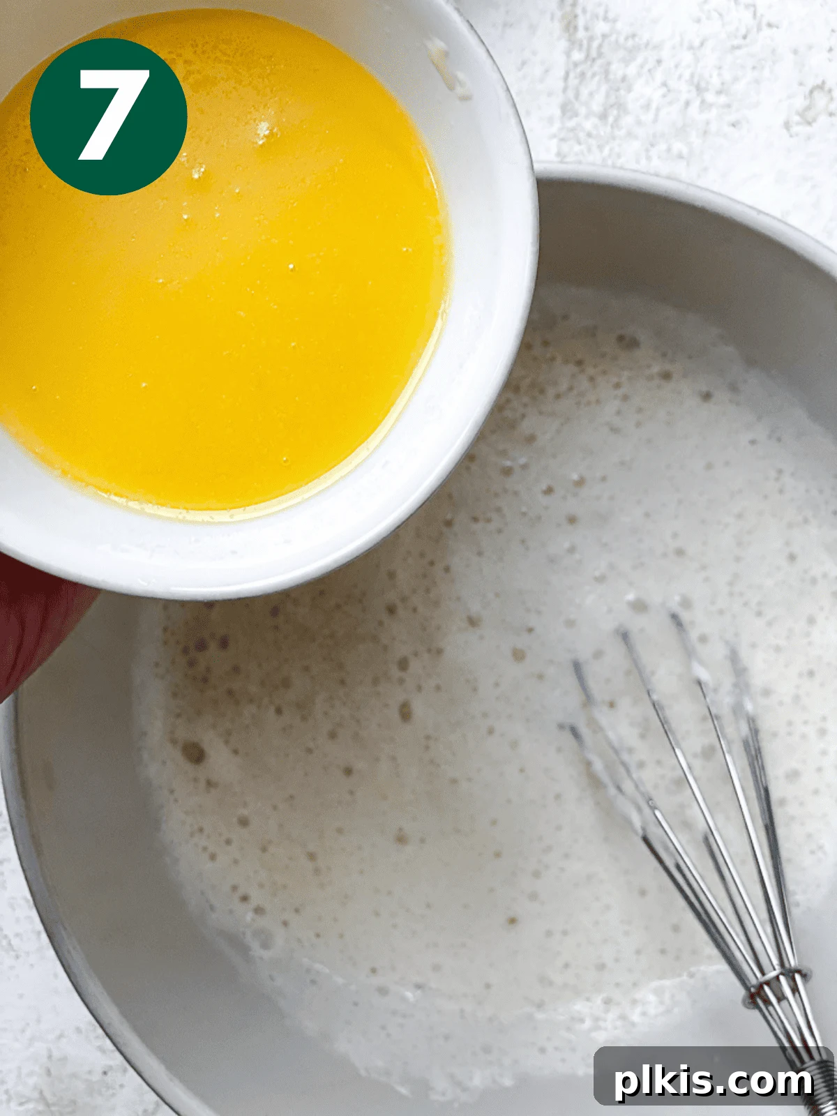 Heavenly Vegan Cinnamon Rolls 10 Melted vegan butter being poured into the wet yeast mixture in a white bowl.