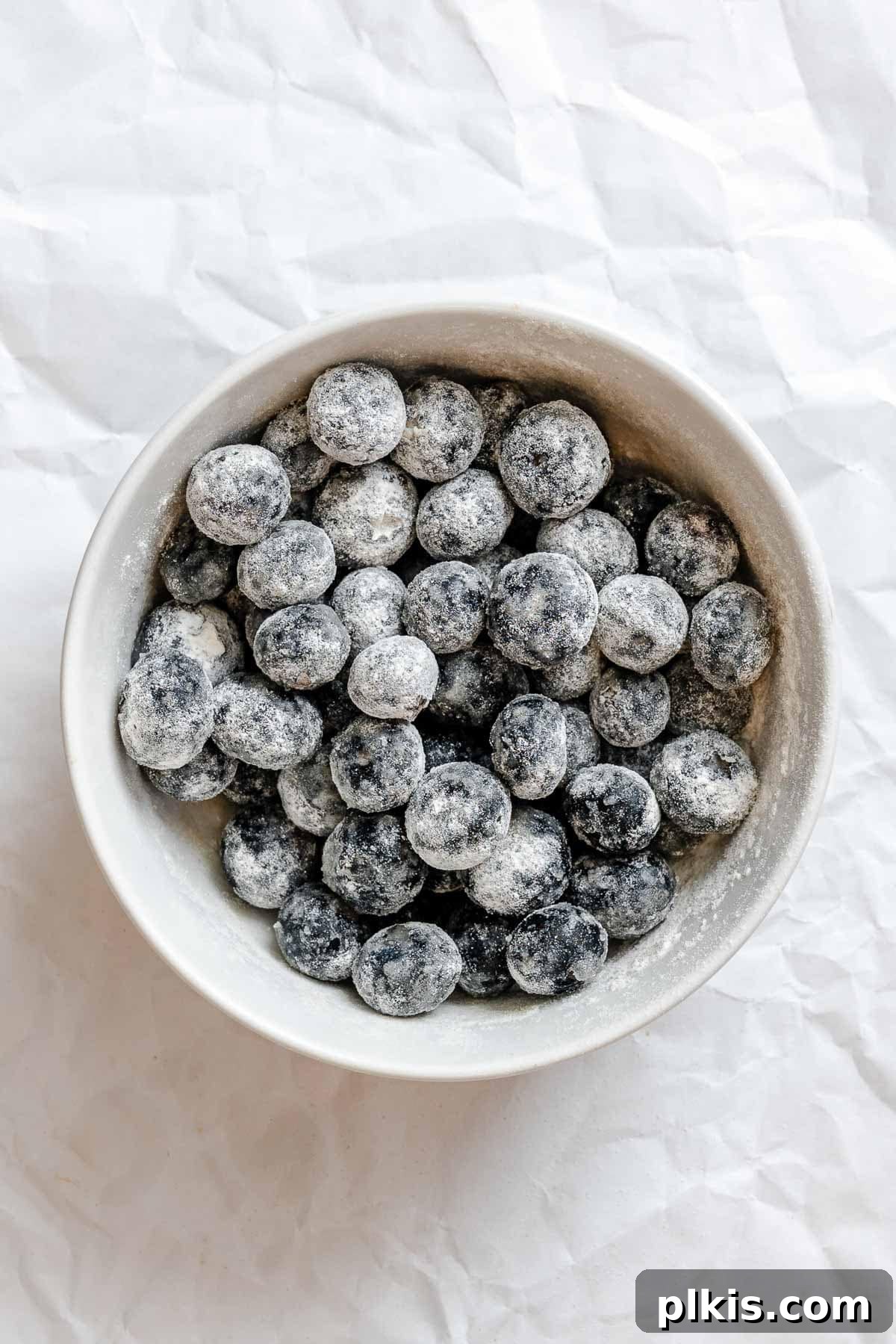 Quick and Easy Blueberry Bread 4 Process shot showing blueberries tossed with flour and sugar in a bowl.