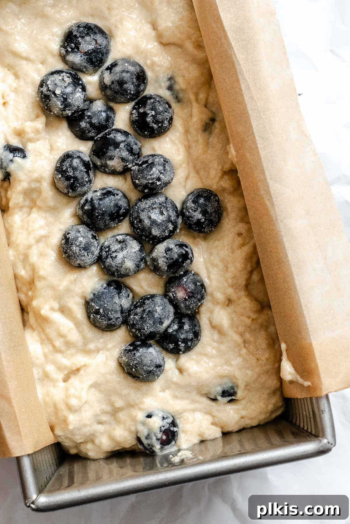 Quick and Easy Blueberry Bread 6 Process shot showing batter and blueberries added to a prepared bread pan, ready for baking.