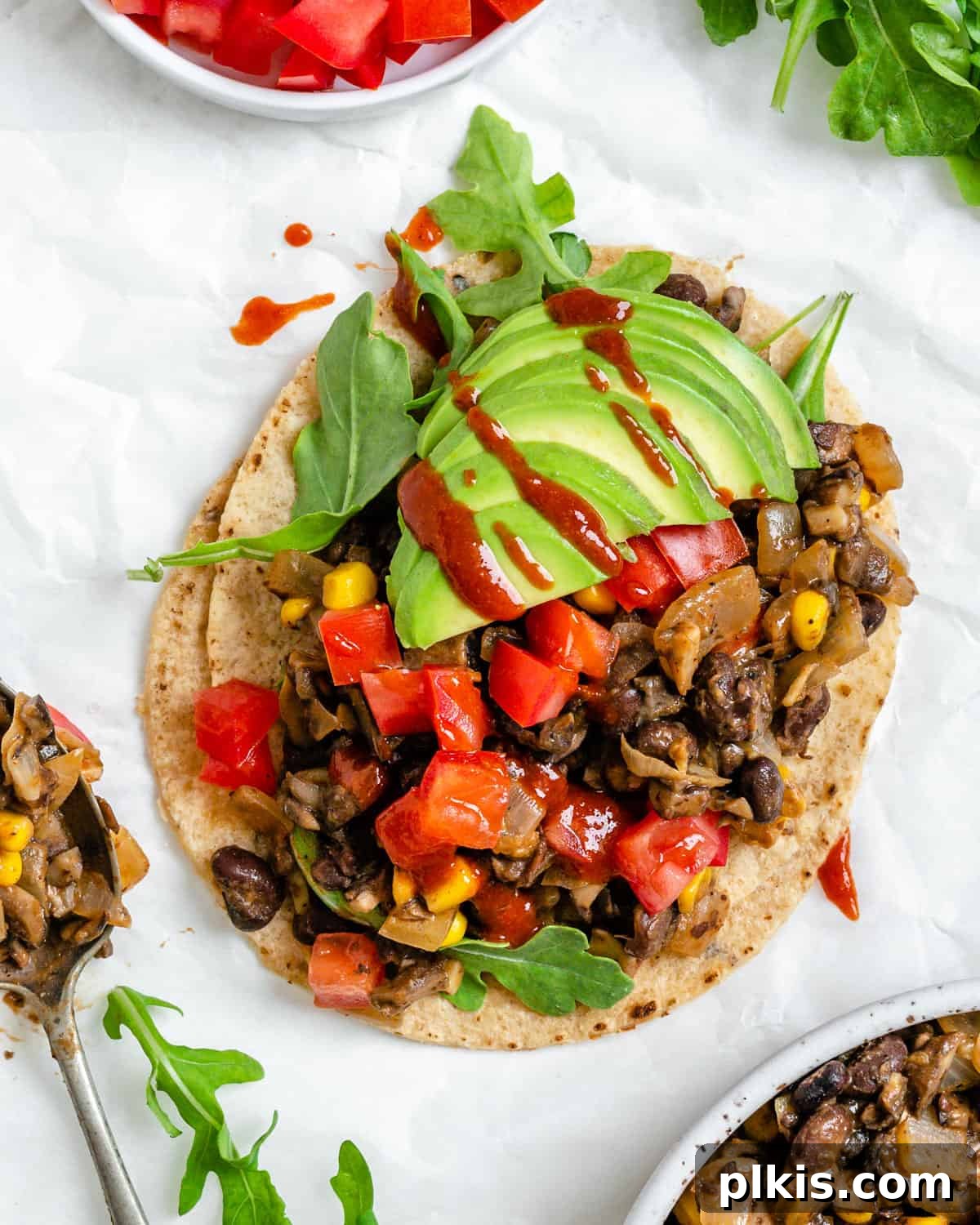 completed Vegan Black Bean Tacos [2 Ways] on a white surface with ingredients scattered in the background