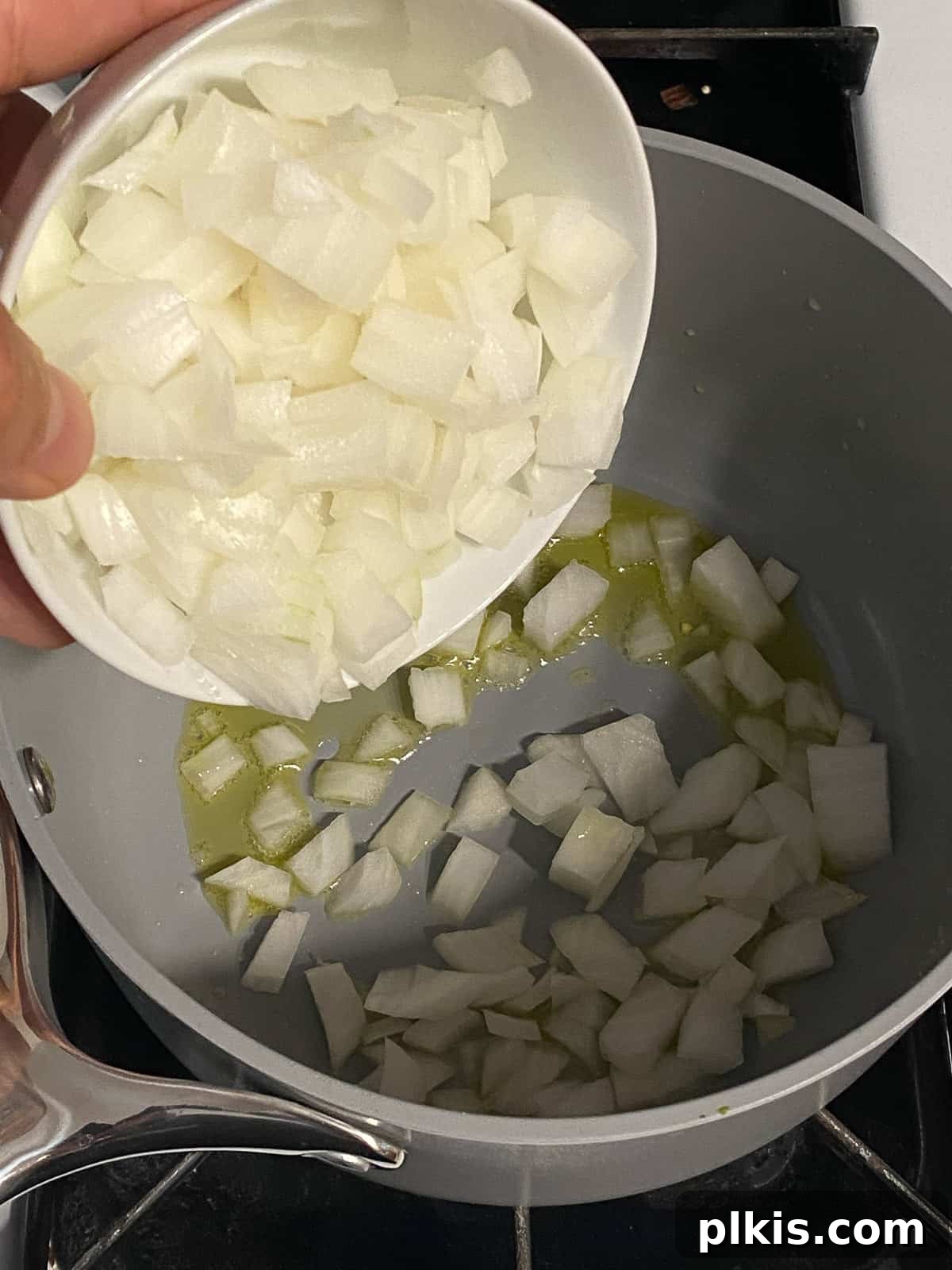 Velvety Vegan Coconut Corn Chowder 5 Step 1: Adding chopped yellow onion to the heated oil in the pot.