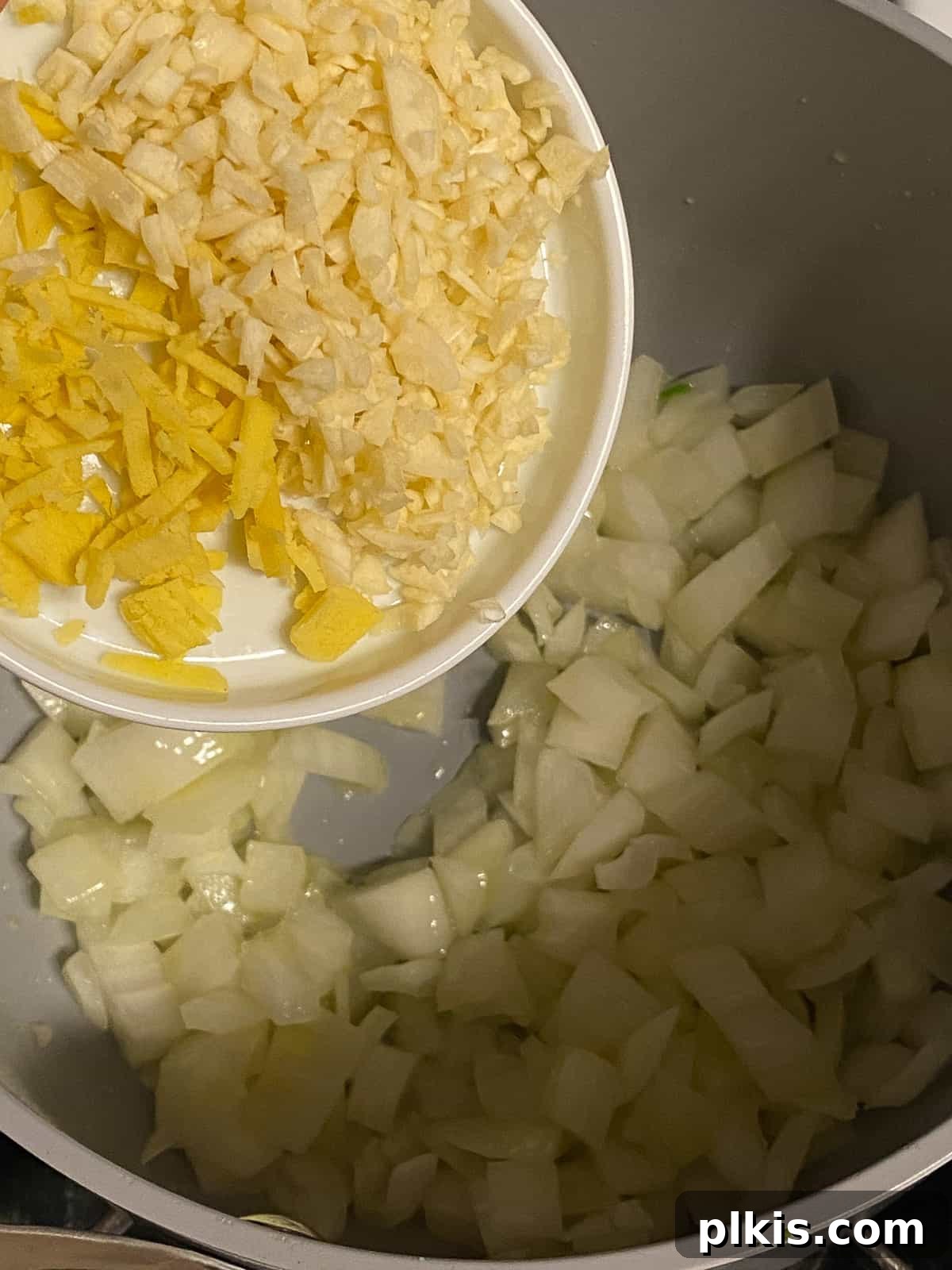 Velvety Vegan Coconut Corn Chowder 6 Step 1: Incorporating chopped garlic and ginger into the pot with the onion.