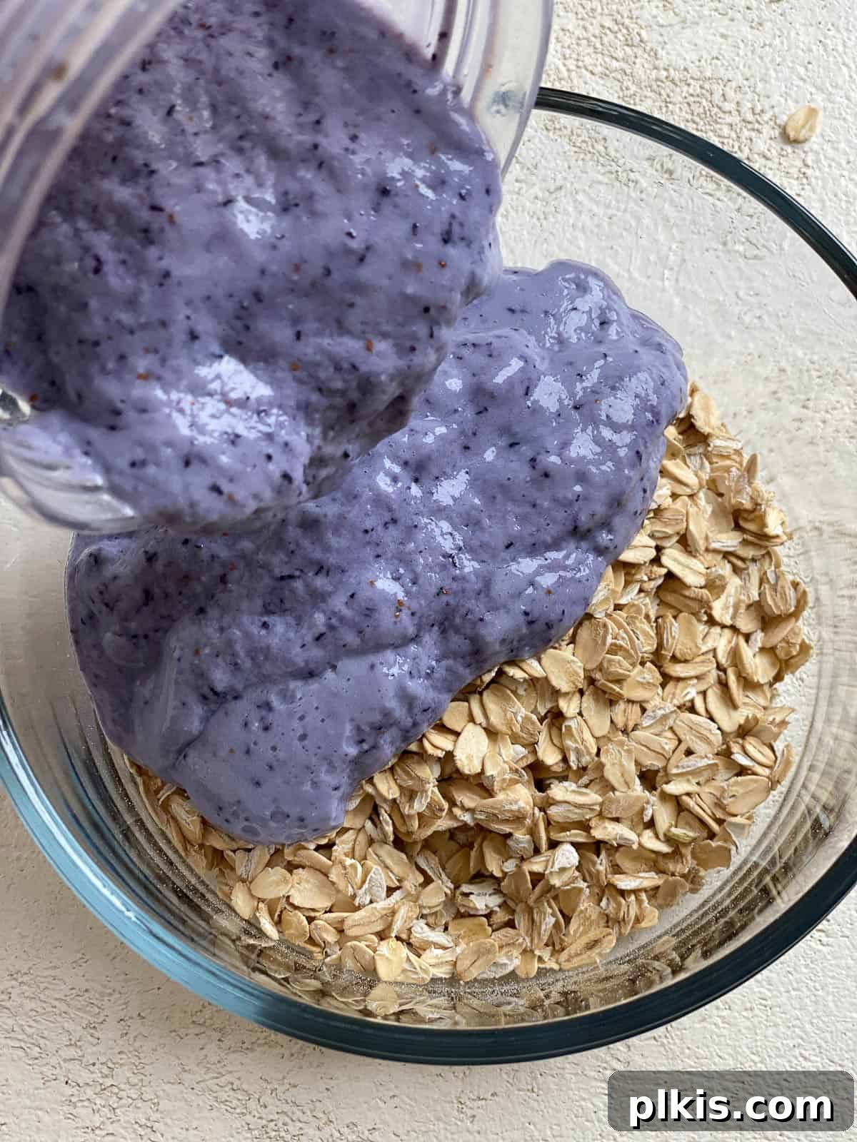 Overnight Blueberry Delight 14 Pouring the blended blueberry mixture over rolled oats in a jar.