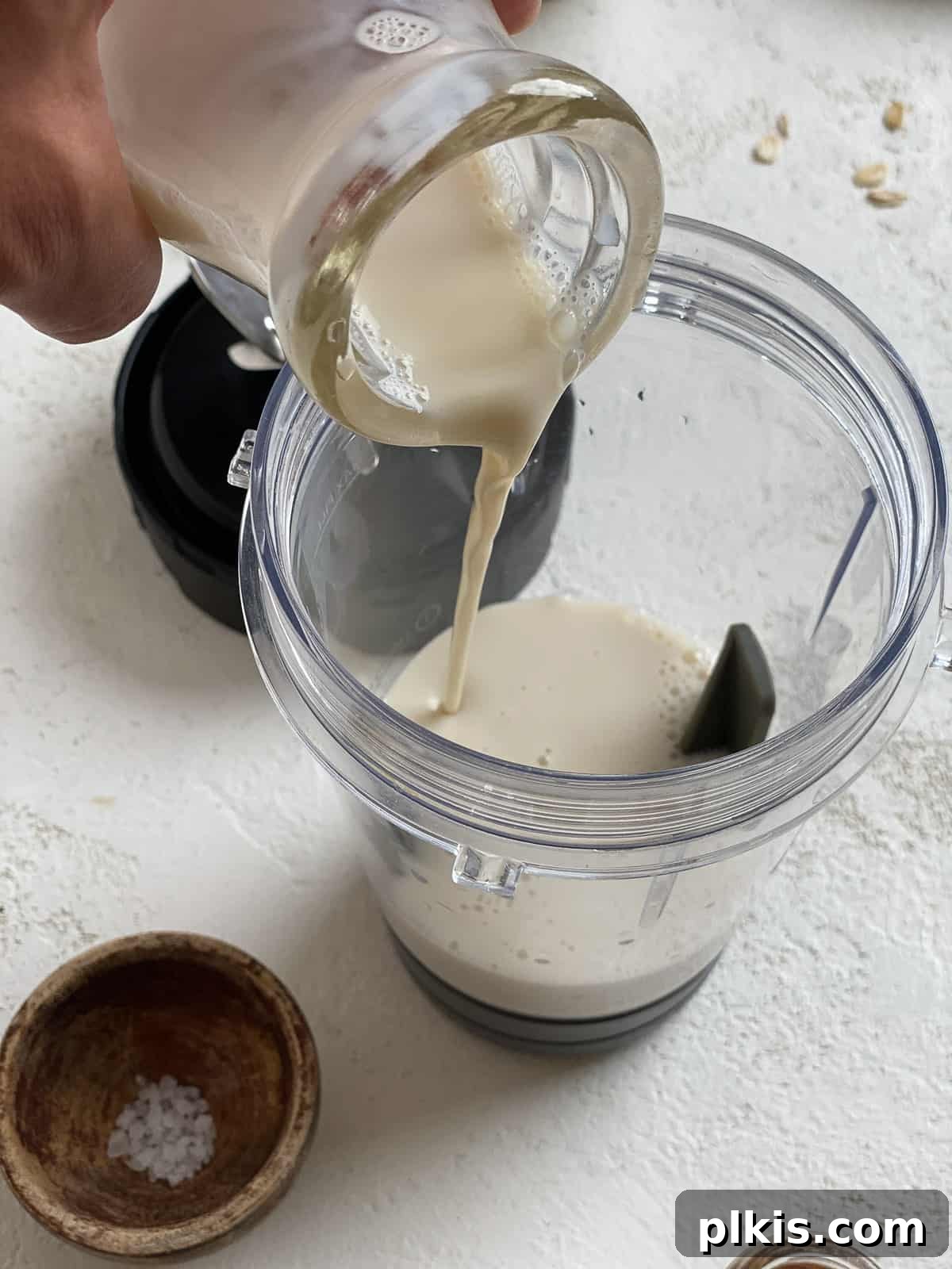 Overnight Blueberry Delight 5 Pouring plant-based milk into a blender for blueberry overnight oats.