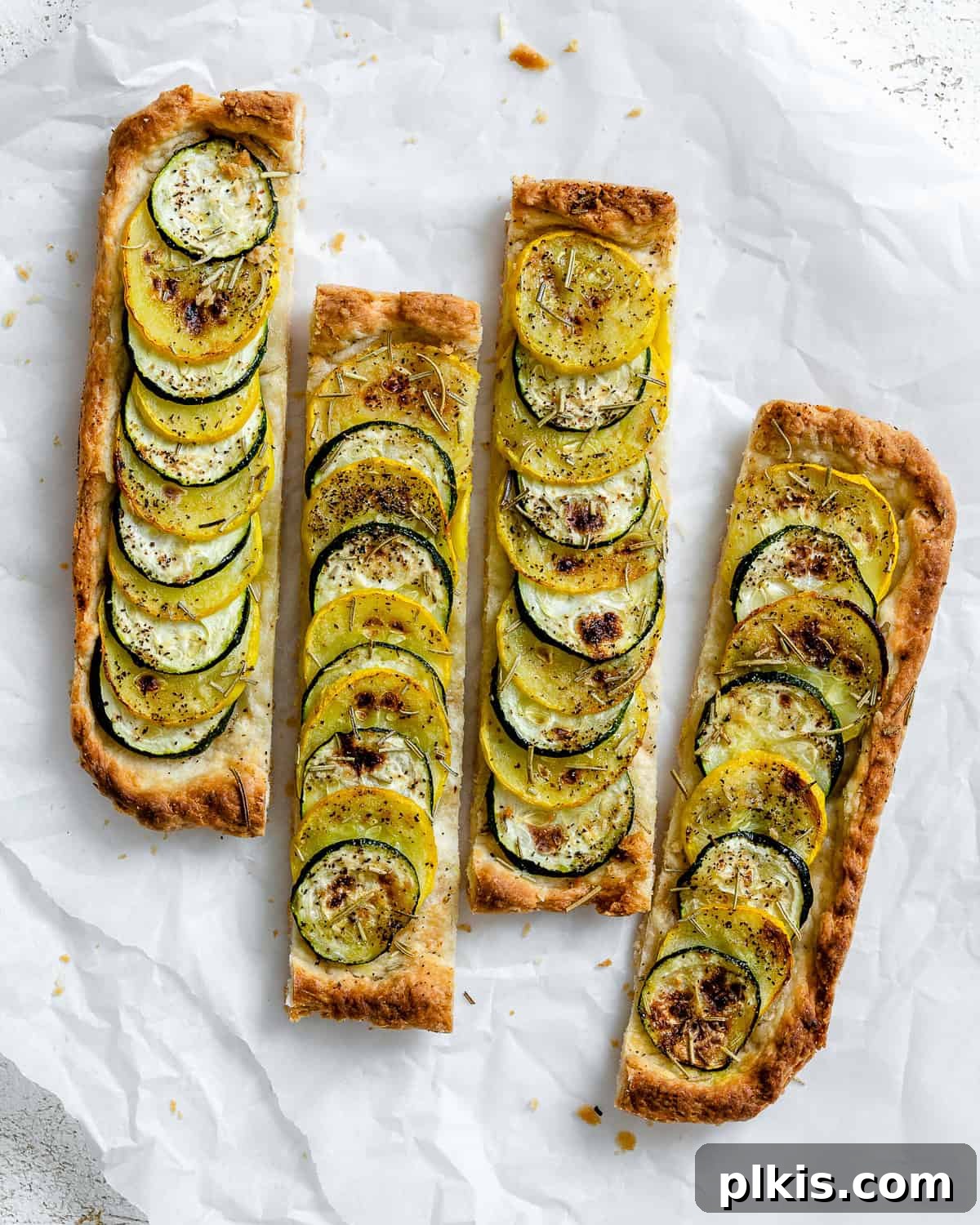 Vibrant Zucchini Tart 2 A beautifully baked and sliced vegan zucchini tart, golden brown and garnished with fresh rosemary.