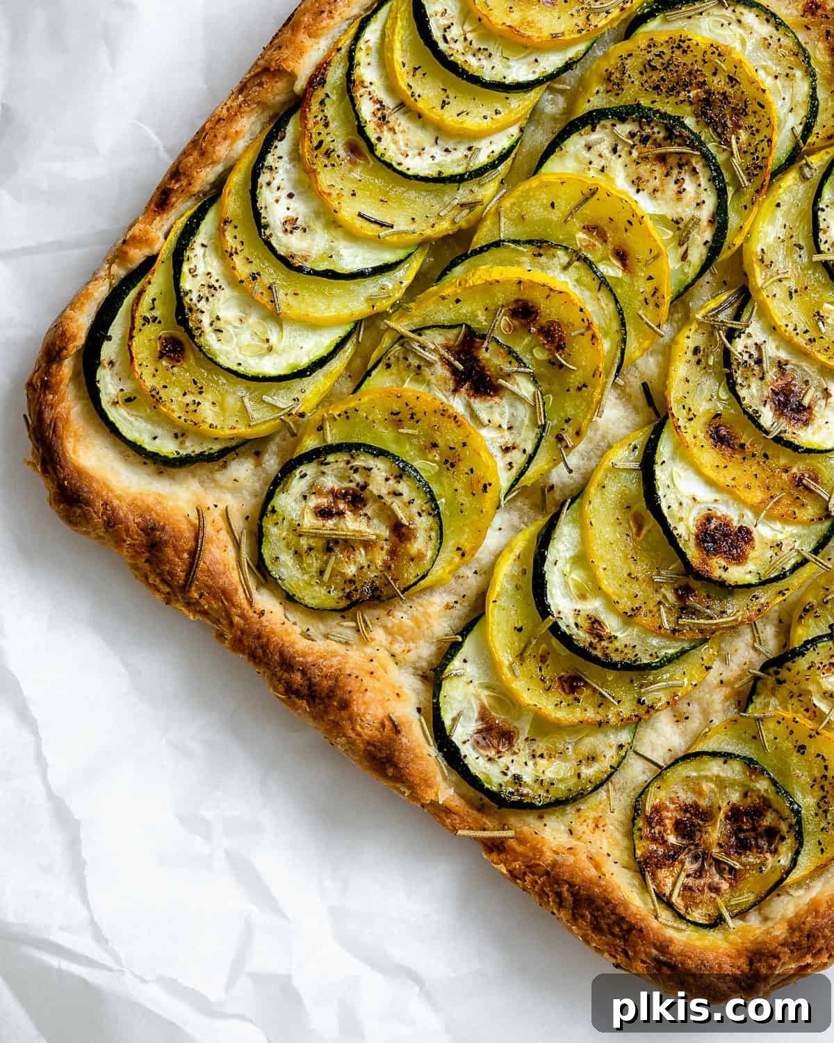 Vibrant Zucchini Tart 11 A freshly baked and golden-brown zucchini tart, resting on parchment paper after being removed from the oven.