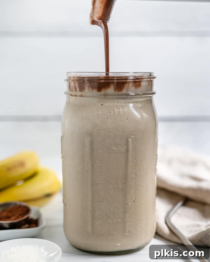 Chocolate Peanut Butter Banana Dream 6 Process shot of pouring the blended chocolate peanut butter mixture over the plain banana smoothie in a jar