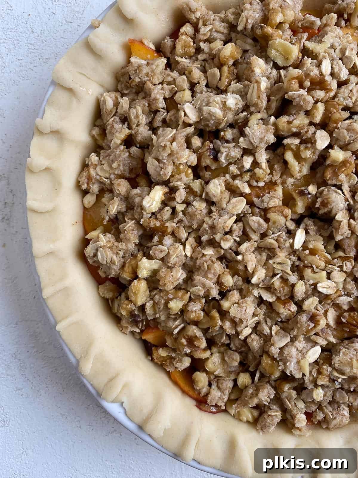 pre-baked peach crumb pie against a white surface
