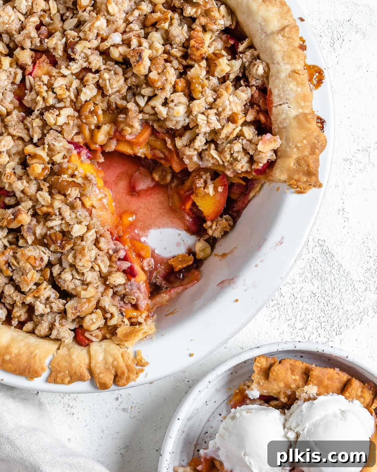 completed Peach Crumb Pie with a slice in a separate white bowl