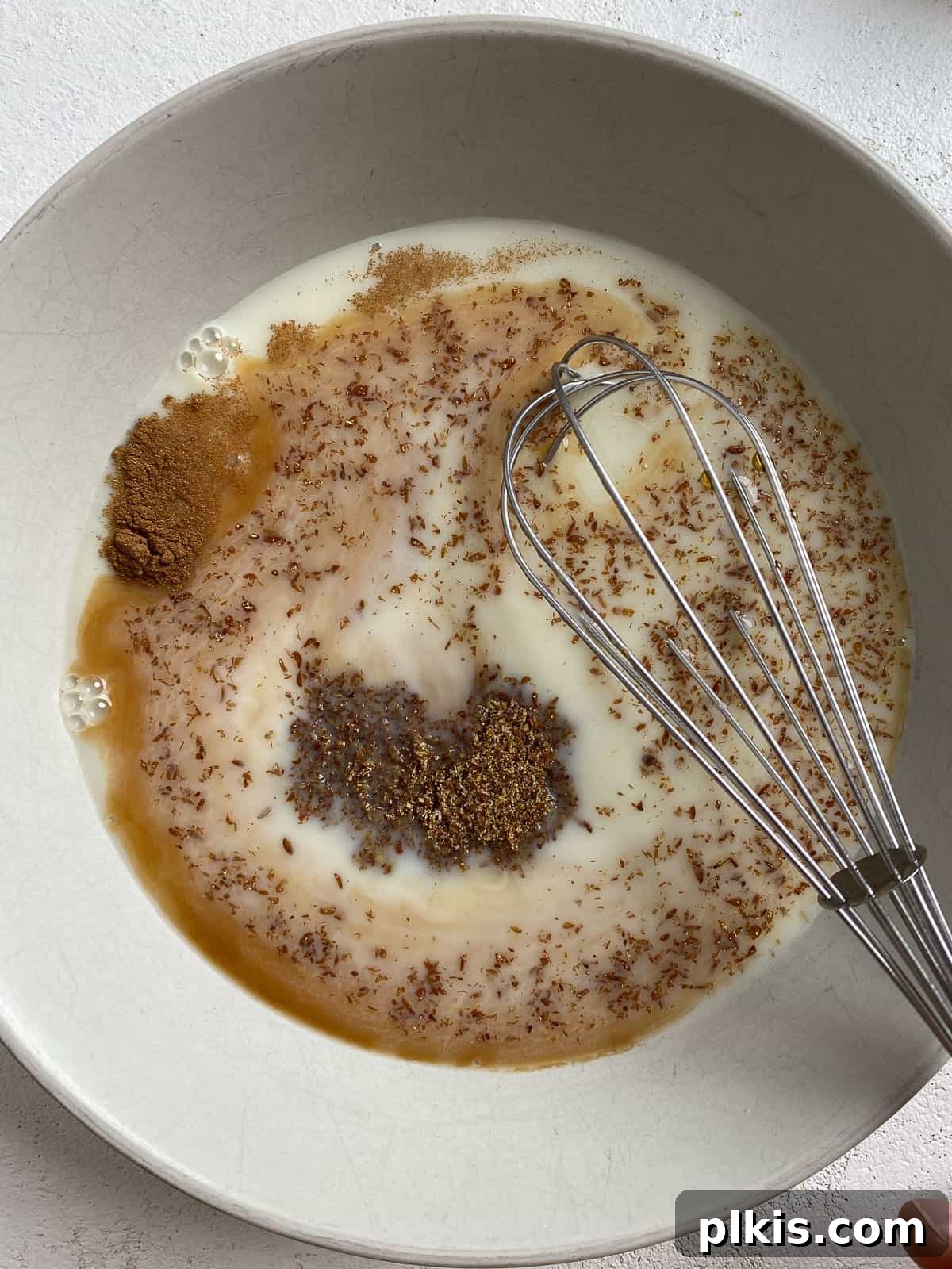 Close-up shot of whisking the vegan French toast batter ingredients in a white bowl, showing the smooth consistency.
