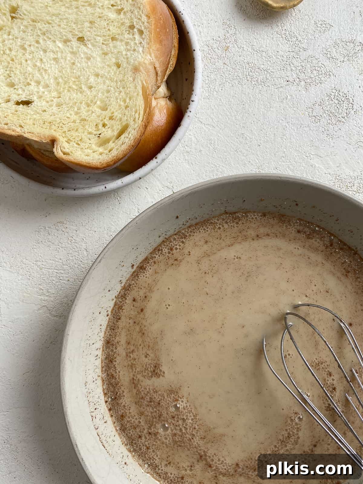 A bowl of vegan French toast batter next to a plate of bread slices, ready for dipping.