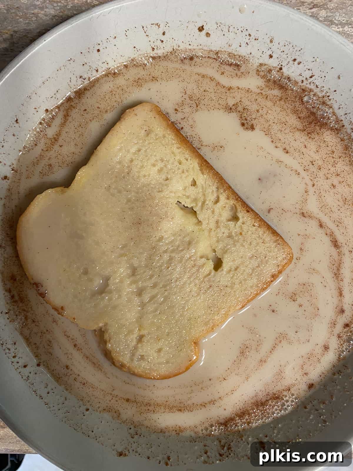 Process shot: A second slice of bread being dipped into the vegan French toast batter, ensuring full coverage.